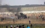 متظاهرون فلسطينيون يحرقون الإطارات وسط اشتباكات مع قوات الأمن الإسرائيلية في أعقاب مظاهرة عند السياج الحدودي مع إسرائيل، شرقي مدينة غزة، في 21 أغسطس، 2021. (SAID KHATIB / AFP)