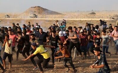 فلسطينيون يفرون من الغاز المسيل للدموع الذي أطلقته قوات الأمن الإسرائيلية على طول السياج الحدودي، شرقي خان يونس جنوب قطاع غزة، 25 أغسطس 2021 (Mahmud Hams / AFP)