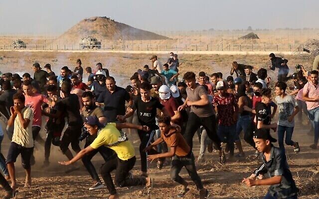 فلسطينيون يفرون من الغاز المسيل للدموع الذي أطلقته قوات الأمن الإسرائيلية على طول السياج الحدودي، شرقي خان يونس جنوب قطاع غزة، 25 أغسطس 2021 (Mahmud Hams / AFP)