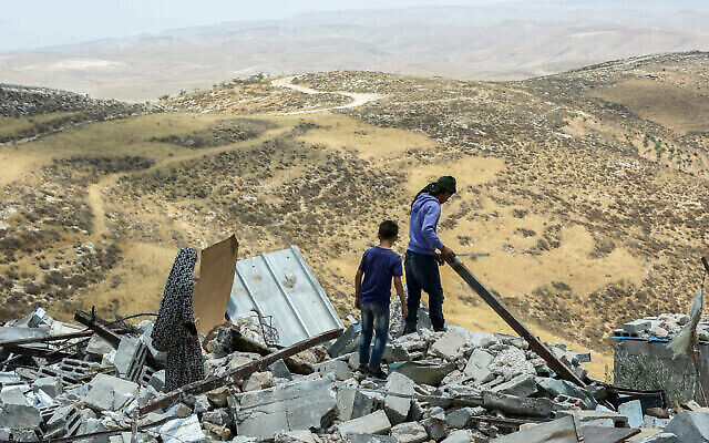فلسطينيون ينظرون إلى منازل هدمتها السلطات الإسرائيلية في قرية خلة الضبع بالضفة الغربية، جنوب يطا، 17 يونيو 2019 (Wissam Hashlamon / Flash90)