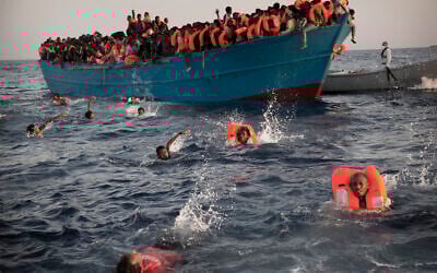 توضيحية: في هذه الصورة المحفوظة في 29 أغسطس 2016 ، مهاجرون، معظمهم من إريتريا، يقفزون في الماء من قارب خشبي مزدحم حيث يساعدهم أعضاء منظمة غير حكومية أثناء عملية إنقاذ في البحر الأبيض المتوسط، على بعد حوالي 13 20 كيلومترا، شمال صبراتة، ليبيا. (AP /Emilio Morenati)