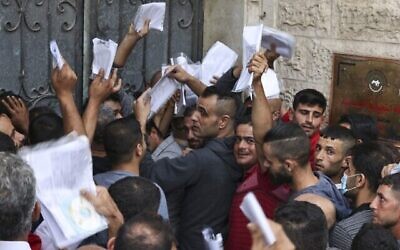 رجال فلسطينيون يتجمعون لتقديم طلبات للحصول على تصاريح عمل في اسرائيل، في مخيم جباليا شمال قطاع غزة، 6 أكتوبر، 2021. (MAHMUD HAMS / AFP)