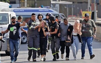 يساعد مسعفون لبنانيون في إجلاء المدنيين خلال الاشتباكات في منطقة الطيونة بالضاحية الجنوبية للعاصمة بيروت في 14 أكتوبر،  2021، إثر مظاهرة نظمها أنصار حزب الله وحركة أمل. (JOSEPH EID / AFP)