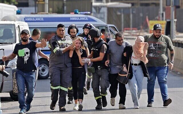 يساعد مسعفون لبنانيون في إجلاء المدنيين خلال الاشتباكات في منطقة الطيونة بالضاحية الجنوبية للعاصمة بيروت في 14 أكتوبر،  2021، إثر مظاهرة نظمها أنصار حزب الله وحركة أمل. (JOSEPH EID / AFP)