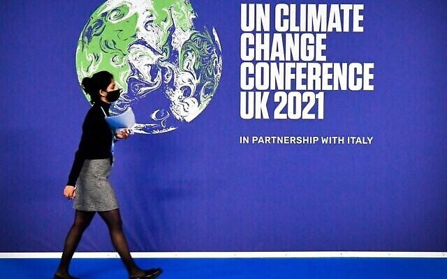 توضيحية: إحدى المشاركات تمر من أمام ملصق مؤتمر الأمم المتحدة لتغير المناخ COP26 في اليوم الأول من المؤتمر في المجمع الاسكتلندي للأحداث (SEC) في غلاسكو، اسكتلندا، 31 أكتوبر، 2021. (ALAIN JOCARD / AFP) توضيحية: إحدى المشاركات تمر من أمام ملصق مؤتمر الأمم المتحدة لتغير المناخ COP26 في اليوم الأول من المؤتمر في المجمع الاسكتلندي للأحداث (SEC) في غلاسكو، اسكتلندا، 31 أكتوبر، 2021. (ALAIN JOCARD / AFP)