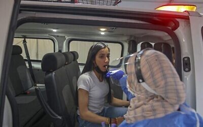 عاملة طبية تأخذ عينة مسحة من امرأة في موقع فحوصات كورونا في القدس، 29 نوفمبر، 2021. (AHMAD GHARABLI / AFP)