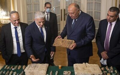 مدير هيئة الآثار الإسرائيلية إيلي إسكوزيدو (إلى اليسار) ينظر إلى وزير الخارجية الإسرائيلي يائير لابيد (مركز يسار) يقدم لوزير الخارجية المصري سامح شكري (مركز وسط) القطع الأثرية المصرية المسروقة التي تم تهريبها إلى إسرائيل وإعادتها إلى مصر، خلال اجتماعهم في قصر التحرير في القاهرة في 9 ديسمبر 2021 (محمد حسام / وكالة الصحافة الفرنسية)