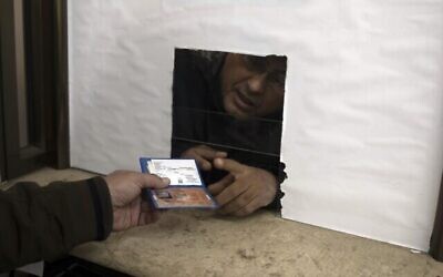 رجل فلسطيني يسلم بطاقة هويته المؤقتة لموظف الشؤون المدنية للحصول على وثيقة تسجيله المعتمد رسميا، في مدينة غزة، 3 يناير، 2022. (AP Photo / Khalil Hamra)