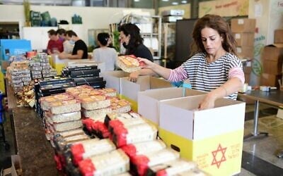 الفنانة الإسرائيلية غاليت غيئات مع متطوعين يعملون على تجهيز رزم مواد غذائية للمحتاجين، 24 نوفمبر، 2020. (Tomer Neuberg / Flash 90)