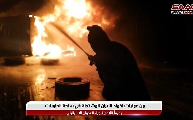 رجل إطفاء سوري يعمل على إخماد حريق ناجم عن غارة جوية إسرائيلية مزعومة على ميناء اللاذقية في 28 ديسمبر، 2021. (Screencapture / YouTube) رجل إطفاء سوري يعمل على إخماد حريق ناجم عن غارة جوية إسرائيلية مزعومة على ميناء اللاذقية في 28 ديسمبر، 2021. (Screencapture / YouTube)