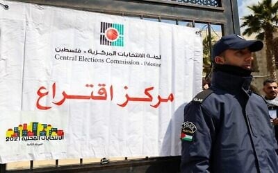 شرطي فلسطيني يحرس محطة اقتراع خلال الانتخابات المحلية في مدينة الخليل بالضفة الغربية، 26 مارس، 2022. (Hazem Bader / AFP)