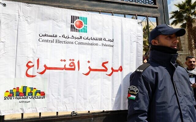 شرطي فلسطيني يحرس محطة اقتراع خلال الانتخابات المحلية في مدينة الخليل بالضفة الغربية، 26 مارس، 2022. (Hazem Bader / AFP)