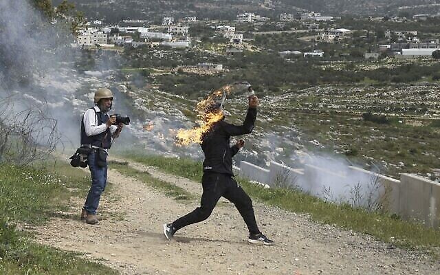 توضيحية: فلسطيني يلقي زجاجة حارقة وسط مواجهات مع القوات الإسرائيلية، خلال مظاهرة بمناسبة يوم الأرض في قرية بلعين بالضفة الغربية، 1 أبريل، 2022 (Abbas Momani / AFP) توضيحية: فلسطيني يلقي زجاجة حارقة وسط مواجهات مع القوات الإسرائيلية، خلال مظاهرة بمناسبة يوم الأرض في قرية بلعين بالضفة الغربية، 1 أبريل، 2022 (Abbas Momani / AFP)