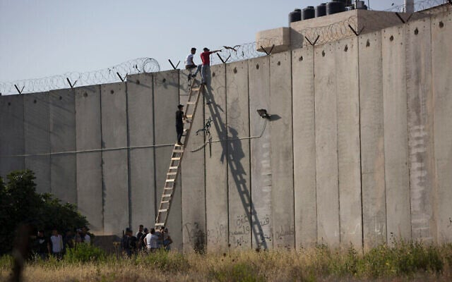 فلسطينيون يتسلقون الجدار الفاصل بالقرب من الرام في طريقهم لأداء صلاة الجمعة في الأقصى، 8 يونيو، 2018. (AP Photo / Majdi Mohammed)