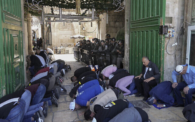 قوات الأمن الإسرائيلية تقوم بالحراسة بينما يؤدي رجال فلسطينيون صلاة الجمعة الثانية من شهر رمضان المبارك أمام قبة الصخرة في الحرم القدسي في البلدة القديمة بالقدس، 15 أبريل، 2022. (AP / Mahmoud إلين) قوات الأمن الإسرائيلية تقوم بالحراسة بينما يؤدي رجال فلسطينيون صلاة الجمعة الثانية من شهر رمضان المبارك أمام قبة الصخرة في الحرم القدسي في البلدة القديمة بالقدس، 15 أبريل، 2022. (AP / Mahmoud إلين)