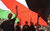 فلسطينيون  يلوحون بالأعلام الفلسطينية ويحملون نماذج مفاتيح عملاقة (رمز يستخدم على نطاق واسع للنكبة ، حيث احتفظ العديد من الفلسطينيين بمفاتيح منازلهم عندما أجبروا على النزوح في عام 1948)، خلال مسيرة لإحياء الذكرى الـ 74 للنكبة، في مدينة رام الله الضفة الغربية، 15 مايو، 2022. (ABBAS MOMANI / AFP)