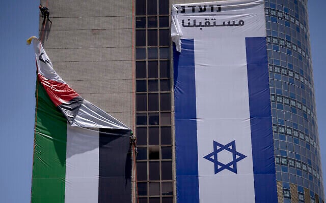 إزالة علم فلسطيني عن مبنى من قبل السلطات الإسرائيلية بعد أن رفعته مجموعة مناصرة للتعايش بين الفلسطينيين والإسرائيليين، في رمات غان، 1 يونيو، 2022. (AP Photo / Oded Balilty)