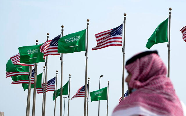 رجل يقف تحت العلمين الأمريكي والسعودي قبل زيارة الرئيس الأمريكي جو بايدن، في ساحة في جدة، المملكة العربية السعودية، 14 يوليو 2022 (AP / Amr Nabil)