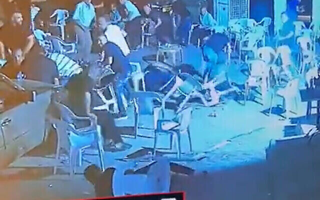 أشخاص يهرعون للاختباء بينما يطلق مسلح النار على تجمع حداد في مدينة كفر قاسم وسط البلاد، 22 يوليو 2022 (Screenshot: Twitter)