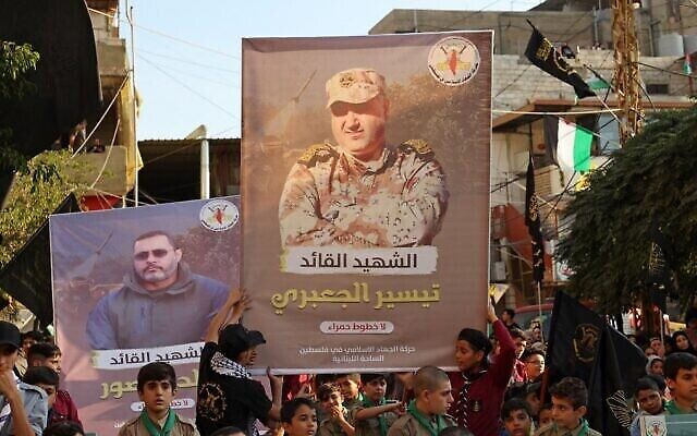 أنصار حركة الجهاد الإسلامي في فلسطين يسيرون مع لافتات تحمل صور القياديين البارزين في الحركة خالد منصور (إلى اليسار) وتيسير الجعبري، اللذين قُتلا في غارات إسرائيلية على قطاع غزة، خلال تظاهرة في مخيم برج البراجنة للاجئين في لبنان، 7 أغسطس، 2022. (Anwar Amro/AFP)