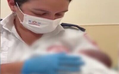 لقطة شاشة من فيديو للمسعفة في نجمة داوود الحمراء مناي جمال مع طفل رضيع تم العثور عليه مهجورًا في أحد شوارع عكا، 8 أغسطس 2022 (Channel 12)