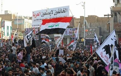 متظاهرون عراقيون يرفعون لافتات وأعلام وطنية خلال مسيرة لإحياء ذكرى مرور ثلاث سنوات على اندلاع المظاهرات في جميع أنحاء البلاد ضد الفساد المستشري، في ساحة الحبوبي في مدينة الناصرية الجنوبية، 1 أكتوبر 2022 (Asaad NIAZI / AFP)