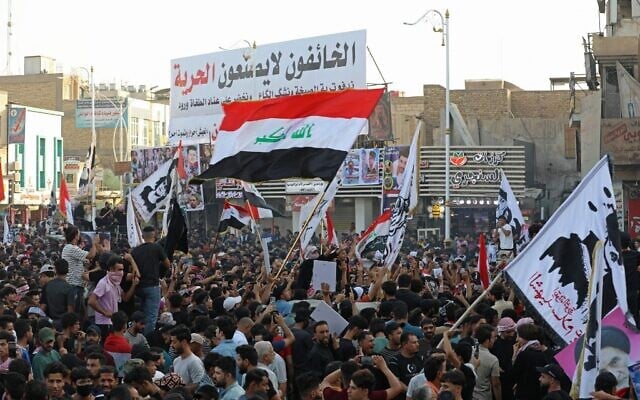 متظاهرون عراقيون يرفعون لافتات وأعلام وطنية خلال مسيرة لإحياء ذكرى مرور ثلاث سنوات على اندلاع المظاهرات في جميع أنحاء البلاد ضد الفساد المستشري، في ساحة الحبوبي في مدينة الناصرية الجنوبية، 1 أكتوبر 2022 (Asaad NIAZI / AFP)