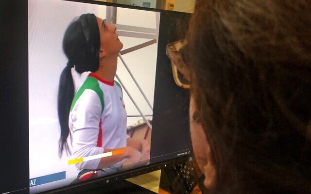 امرأة تنظر إلى شاشة تعرض مقطع فيديو لمسابقة تسلق دولية في سيول، كوريا الجنوبية، شاركت فيها المتسلقة الإيرانية إلناز ركابي بدون حجاب، في العاصمة القبرصية نيقوسيا، 18 أكتوبر 2022 (AFP)