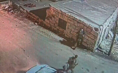 جندي إسرائيلي يدفع رجلا فلسطينيا باتجاه جدار في مدينة الخليل بالضفة الغربية، 23 أكتوبر 2022 (Screenshot: Twitter)