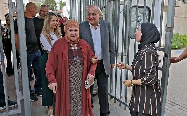 أحمد الطيبي (من الوسط إلى اليمين)، رئيس حزب الحركة العربية من أجل التغيير ، يسير مع والدته (وسط الصورة) بعد التصويت في مركز اقتراع في مدينة الطيبة العربية في وسط إسرائيل خلال الانتخابات العامة في 1 نوفمبر، 2022. (AHMAD GHARABLI / AFP)