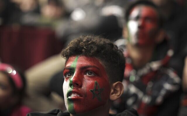 مشجعو كرة قدم فلسطينيين، مع ألوان العلمين الفلسطيني والمغربي على وجوههم، يشاهدون مباراة الجولة السادسة عشر من كأس العالم قطر 2022 بين البرتغال والمغرب، في مدينة غزة، 10 ديسمبر 2022 (MOHAMMED ABED / AFP)