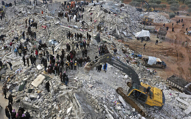 عمال دفاع مدني وسكان يفتشون بين أنقاض المباني المنهارة في بلدة حارم بالقرب من الحدود التركية، محافظة إدلب، سوريا، 6 فبراير،  2023. (AP Photo / Ghaith Alsayed)