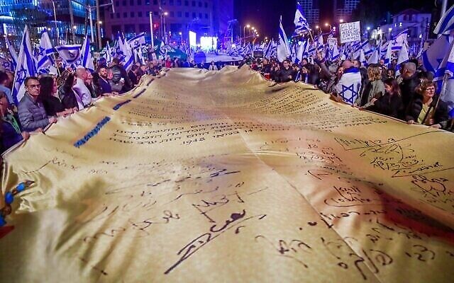 متظاهرون يحملون  وثيقة الاستقلال خلال مظاهرة  حاشدة في تل أبيب للاحتجاج على الإصلاح الشامل الذي تخطط له الحكومة الإسرائيلية للنظام القضائي، 18 فبراير، 2023. (Avshalom Sassoni / Flash90)