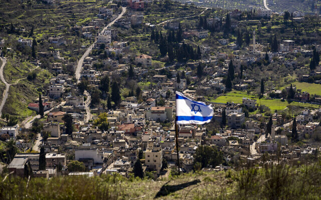 قرية برقة الفلسطينية خلف علم اسرائيلي في بؤرة "حومش" الاستيطانية غير القانونية بالضفة الغربية، 17 يناير 2022 (AP / Ariel Schalit) قرية برقة الفلسطينية خلف علم اسرائيلي في بؤرة "حومش" الاستيطانية غير القانونية بالضفة الغربية، 17 يناير 2022 (AP / Ariel Schalit)
