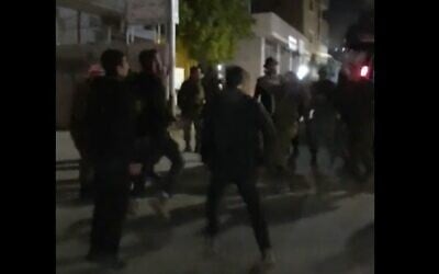 مستوطنون يحتفلون بعيد البوريم ويرقصون مع جنود الجيش الإسرائيلي في بلدة حوارة بالضفة الغربية، 6 مارس 2023 (Screenshot/Twitter; used in accordance with Clause 27a of the Copyright Law)