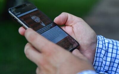 ملف: الصحفي الاستقصائي المجري زابولكس بانيي، الذي كان رقمه مدرجًا في قائمة مسربة للهواتف التي ورد أنها استهدفت بواسطة برامج تجسس إسرائيلية الصنع، ينظر إلى هاتفه المحمول، في بودابست، 20 يوليو 2021 (GERGELY BESENYEI / AFP)