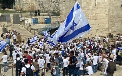 شبان إسرائيليون يرقصون مع الأعلام الإسرائيلية عند باب العامود في البلدة القديمة في القدس في 29 مايوـ 2022، خلال مسيرة لليمنين المتطرف للاحتفال بـ"يوم القدس". (Aaron Boxerman/Times of Israel)