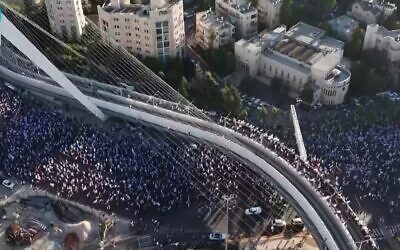 عشرات الآلاف من المتظاهرين يسيرون إلى القدس، تحت جسر الأوتار عند مدخل المدينة، في ختام مسيرة استمرت عدة أيام انطلقت في تل أبيب للاحتجاج على الإصلاح القضائي للحكومة، 22 يوليو 2023 (Channel 13 screenshot; used in accordance with clause 27a of the Copyright Law)