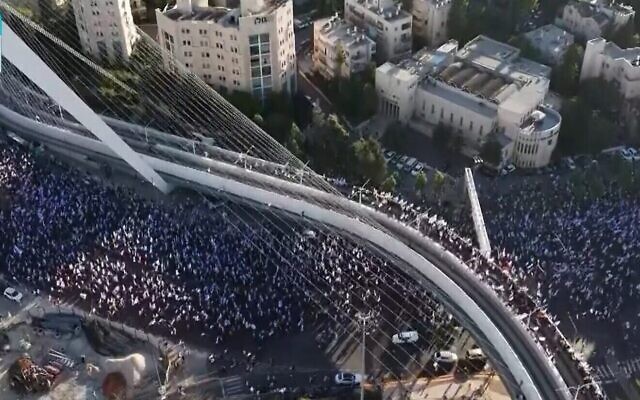 عشرات الآلاف من المتظاهرين يسيرون إلى القدس، تحت جسر الأوتار عند مدخل المدينة، في ختام مسيرة استمرت عدة أيام انطلقت في تل أبيب للاحتجاج على الإصلاح القضائي للحكومة، 22 يوليو 2023 (Channel 13 screenshot; used in accordance with clause 27a of the Copyright Law)