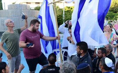 ناشطون علمانيون يزيلون حاجزا للفصل بين الجنسين أقامته جماعة "روش يهودي" في تحد لأمر المحكمة العليا خلال صلاة عامة في ميدان ديزنغوف، تل أبيب، يوم الغفران. 24 سبتمبر 2023. (Tomer Neuberg/Flash 90)