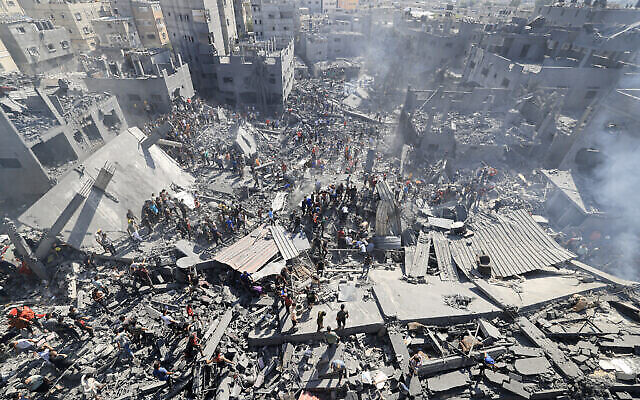 أشخاص يبحثون عن ناجين وجثث ضحايا بين أنقاض المباني التي دمرت خلال الغارات الجوية الإسرائيلية، في خان يونس بجنوب قطاع غزة، 26 أكتوبر، 2023، وسط الحرب المستمرة بين إسرائيل وحركة حماس الفلسطينية. (Mahmud Hams/AFP)