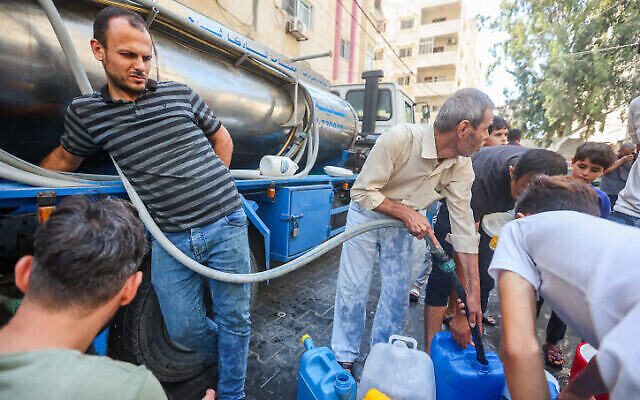 فلسطيني يملأ حاويات المياه في أحد شوارع مدينة غزة، 12 أكتوبر، 2023. (Atia Khaled/Flash90)