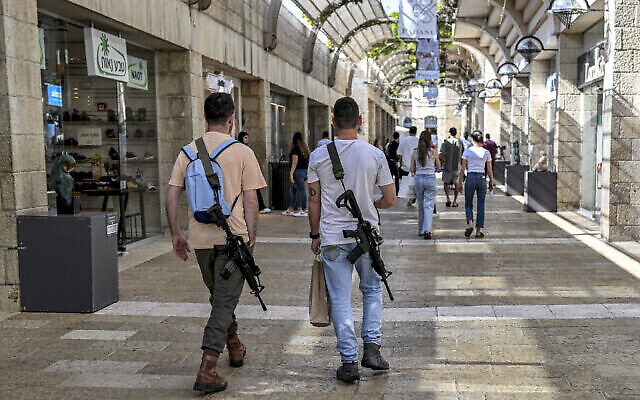 توضيحية: رجلان إسرائيليان، مسلحان ببندقيتين هجوميتين أوتوماتيكيتين أمريكيتي الصنع من طراز M16، يسيران في مركز ماميلا للتسوق في القدس، 25 أكتوبر، 2023. (Yuri Cortez/AFP) توضيحية: رجلان إسرائيليان، مسلحان ببندقيتين هجوميتين أوتوماتيكيتين أمريكيتي الصنع من طراز M16، يسيران في مركز ماميلا للتسوق في القدس، 25 أكتوبر، 2023. (Yuri Cortez/AFP)