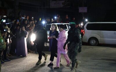 مسلحو حماس يرافقون رهائن إسرائيليين قبل تسليمهم إلى الصليب الأحمر في رفح، في جنوب قطاع غزة، 28 نوفمبر، 2023. (SAID KHATIB / AFP)