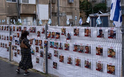 امرأة تنظر إلى صور رهائن محتجزين في غزة معلقة في رمات غان، 22 نوفمبر، 2023. (AP Photo/Oded Balilty)