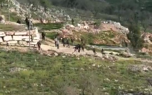 توضيحية: مستوطنون ملثمون يلقون الحجارة على منازل فلسطينية في قرية بورين شمال الضفة الغربية، 3 مارس، 2023. (Yesh Din) توضيحية: مستوطنون ملثمون يلقون الحجارة على منازل فلسطينية في قرية بورين شمال الضفة الغربية، 3 مارس، 2023. (Yesh Din)