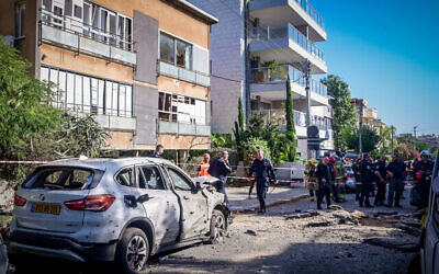 قوات الأمن والإنقاذ الإسرائيلية في موقع سقوط صاروخ أطلقه مسلحون فلسطينيون من قطاع غزة وألحق أضرارا في حولون، 11 ديسمبر، 2023. (Avshalom Sassoni/Flash90)