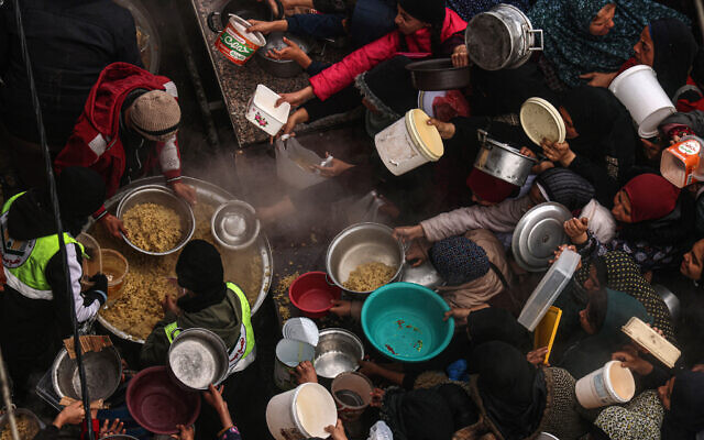 فلسطينيون يحصلون على حصص غذائية في مخيم للنازحين في رفح بجنوب قطاع غزة، 2 فبراير، 2024. (Said Khatib/AFP) فلسطينيون يحصلون على حصص غذائية في مخيم للنازحين في رفح بجنوب قطاع غزة، 2 فبراير، 2024. (Said Khatib/AFP)