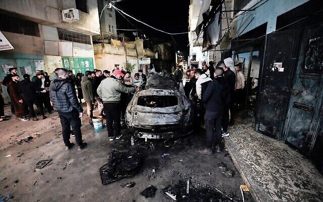 أشخاص يتفقدون سيارة محترقة في غارة إسرائيلية في مدينة جنين بالضفة الغربية خلال الليل، 22 فبراير، 2024. (Mohammad Mansur/AFP) أشخاص يتفقدون سيارة محترقة في غارة إسرائيلية في مدينة جنين بالضفة الغربية خلال الليل، 22 فبراير، 2024. (Mohammad Mansur/AFP)