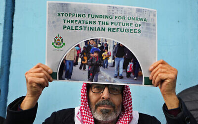 فلسطيني من أنصار حماس يحمل لافتة تحمل شعار الحركة خلال مظاهرة تطالب بإعادة موظفي الأونروا الذين تم فصلهم في قطاع غزة بعد مشاركتهم المزعومة في الفظائع التي وقعت في 7 أكتوبر إلى وظائفهم واستئناف الدول تمويل الوكالة، من أمام مقر وكالة الأمم المتحدة لإغاثة وتشغيل اللاجئين الفلسطينيين في بيروت، لبنان، 30 يناير، 2024.  (AP Photo/Bilal Hussein)